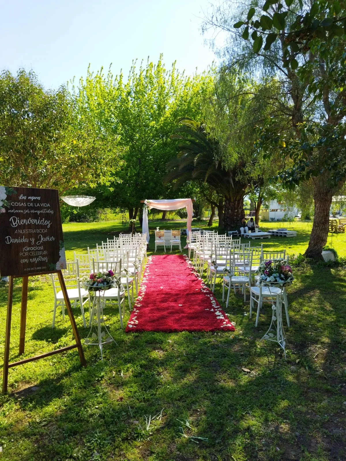 Ceremonia exterior con alfombra roja y sillas blancas